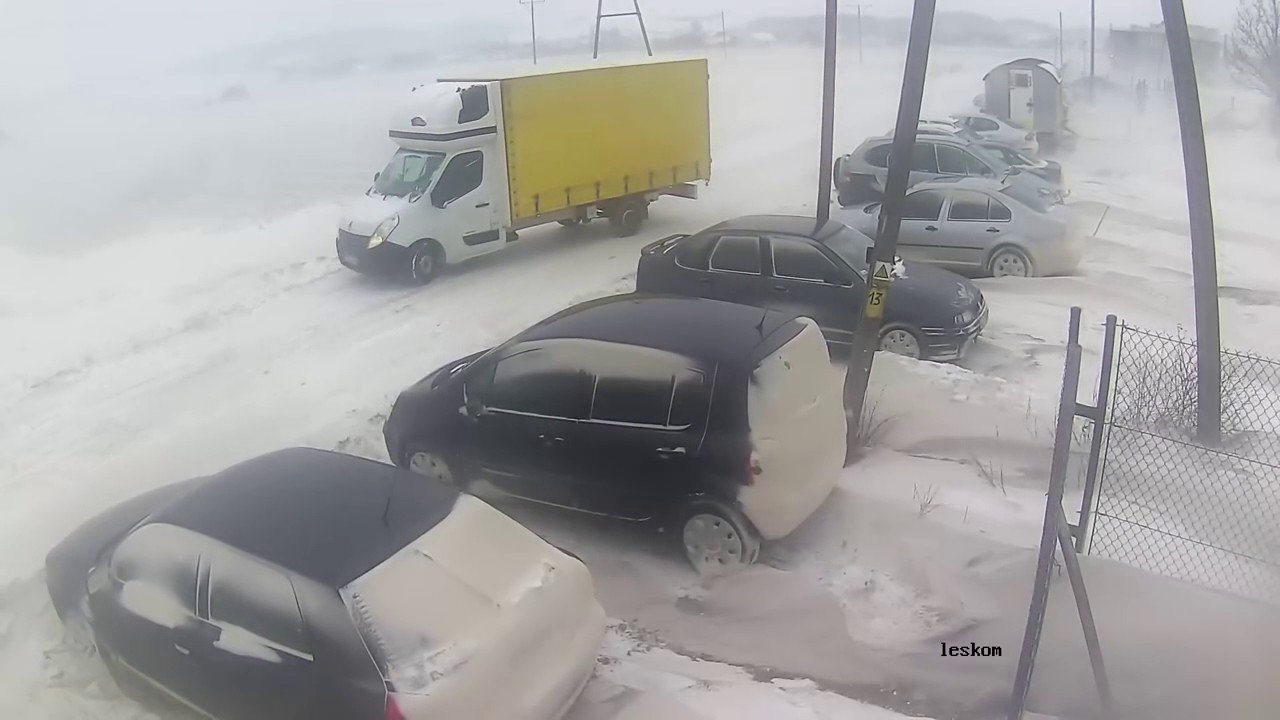 Грузовик на скользкой дороге в ветренную погоду пинает припаркованные машины