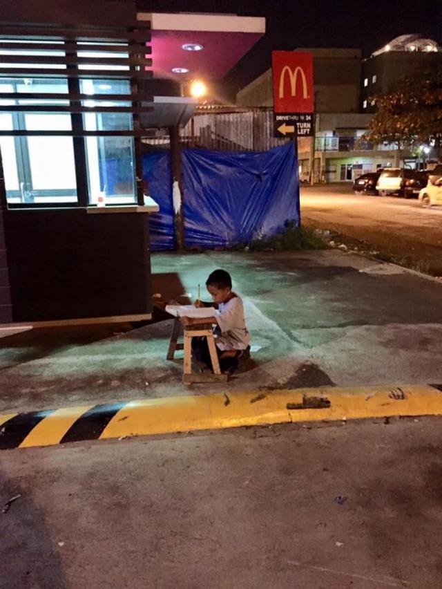 Филиппинский мальчик делает уроки в свете огней Макдональдса (2 фото)