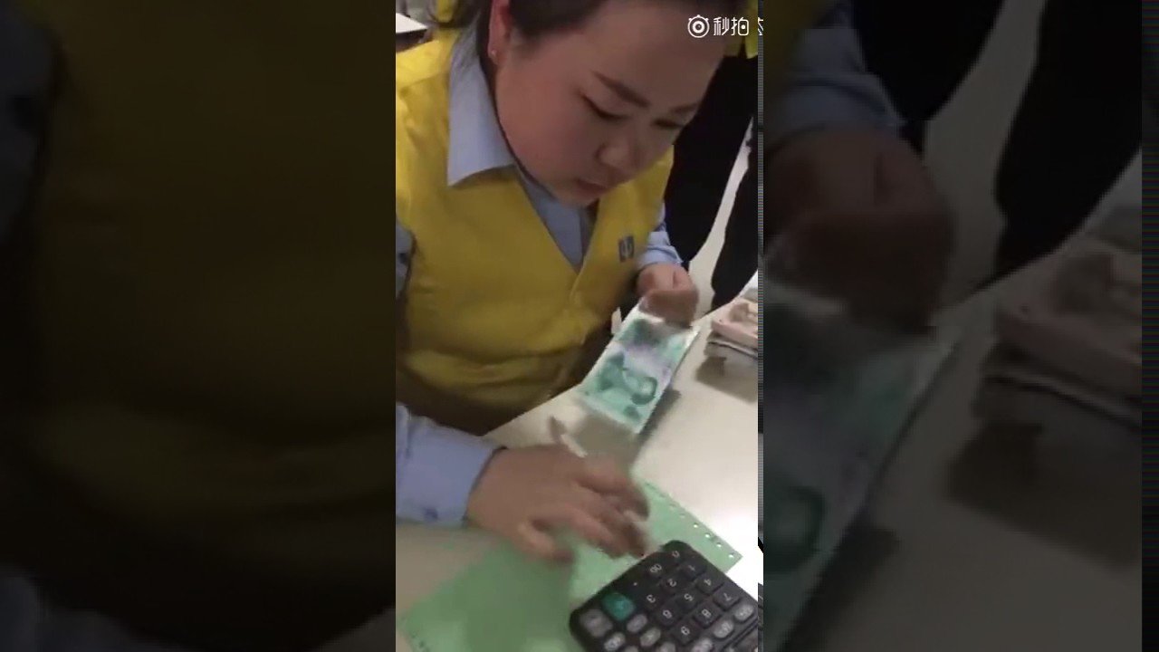 Китаянка считает деньги в банке